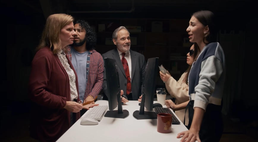 Office team gathered around dual monitors reviewing automated SOP documentation with Scribe