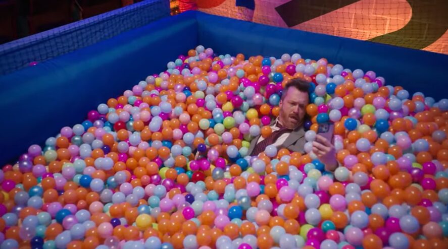 man answering a call in a ballpit for Vonage commercial