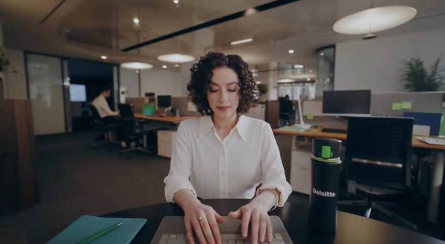 Female office working sitting at a desk for Deloitte commercial