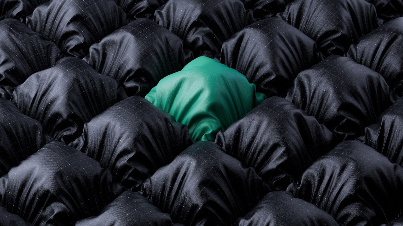 A single teal cushion standing out from a field of identical black ones