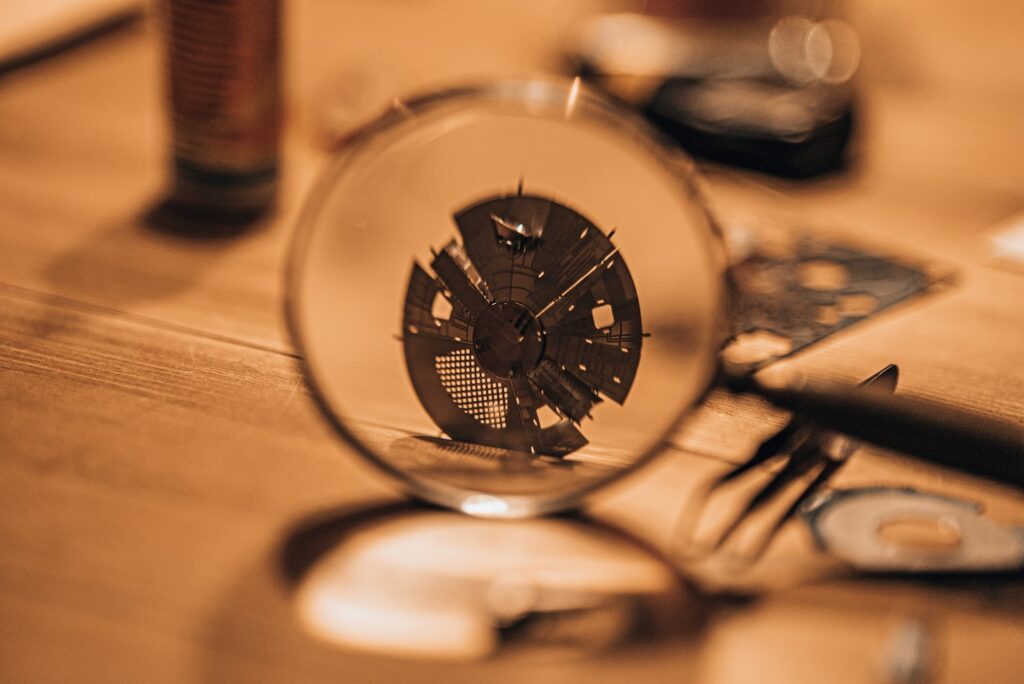 A magnifying loupe held over the exposed mechanism of a watch, lit warm on a workbench.